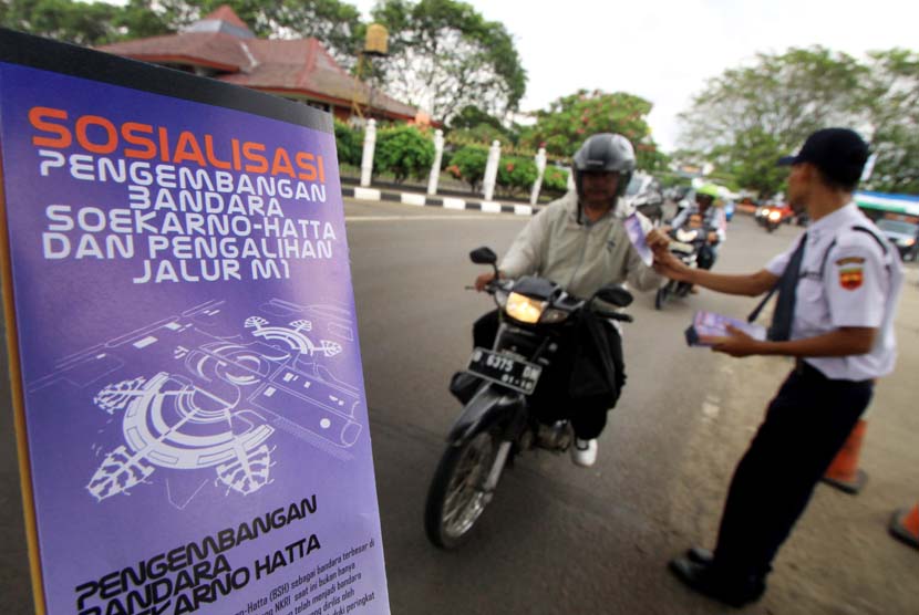 Petugas membagikan brosur sosialisasi pengalihan arus lalu lintas M1 Bandara Soekarno-Hatta, Tangerang, Banten, Selasa (24/12).   (Antara/Rivan Awal Lingga)