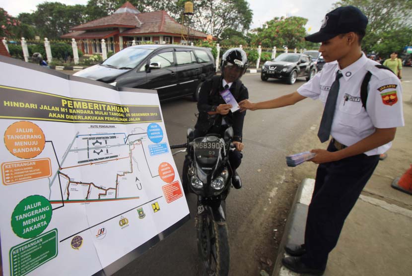Petugas membagikan brosur sosialisasi pengalihan arus lalu lintas M1 Bandara Soekarno-Hatta, Tangerang, Banten, Selasa (24/12).   (Antara/Rivan Awal Lingga)