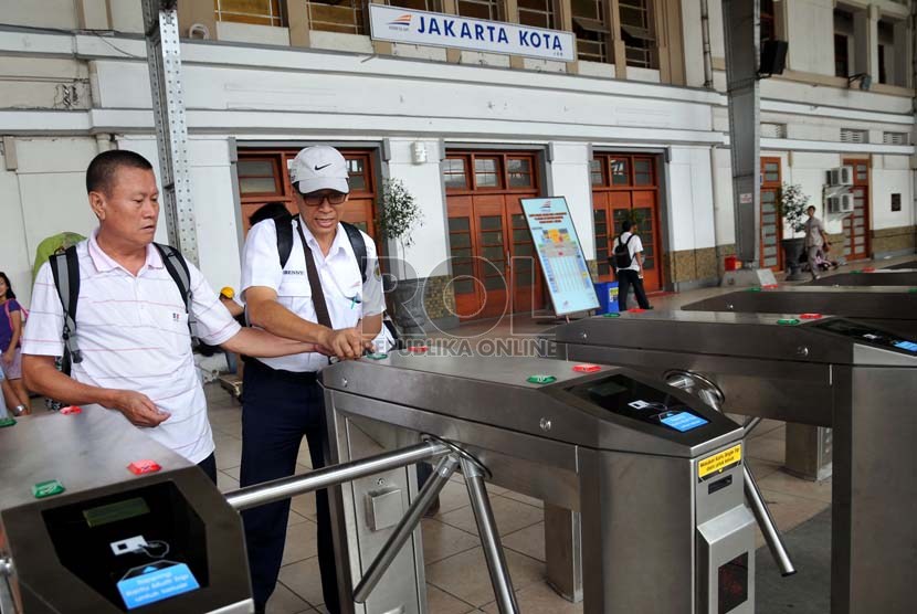  Petugas membantu calon penumpang kereta api listrik (KRL)  menggunakan tiket elektronik (e-ticketing) di Stasiun Jakarta Kota, Selasa (23/4).    (Republika/Prayogi)