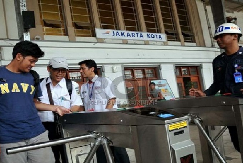 Petugas membantu calon penumpang kereta api listrik (KRL) menggunakan tiket elektronik (e-ticketing) di Stasiun Jakarta Kota, Selasa (23/4).