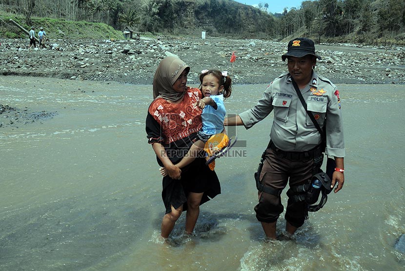 Petugas membantu mengevakuasi warga warga Desa Pandansari yang terputus akses jalannya akibat lahar dingin Gunung Kelud di Kecamatan Ngantang, Malang, Jawa Timur, Kamis (20/2).