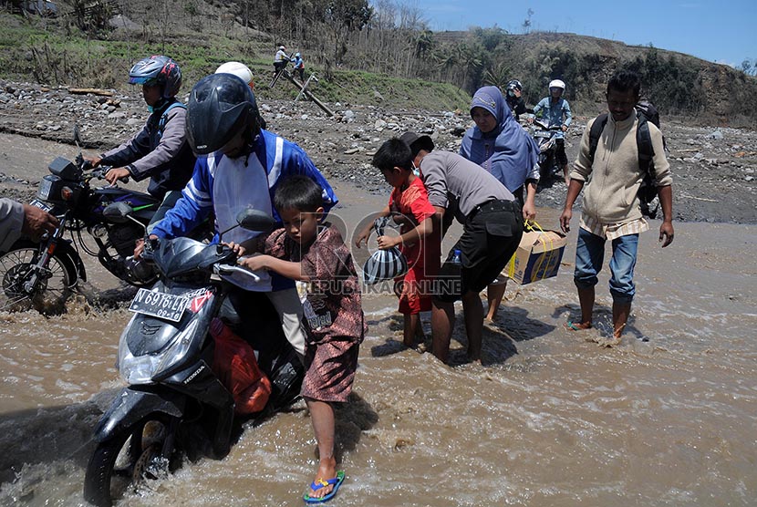 Petugas membantu mengevakuasi warga warga Desa Pandansari yang terputus akses jalannya akibat lahar dingin Gunung Kelud di Kecamatan Ngantang, Malang, Jawa Timur, Kamis (20/2).