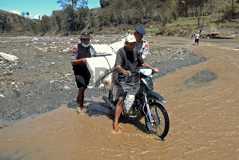 Petugas membantu mengevakuasi warga warga Desa Pandansari yang terputus akses jalannya akibat lahar dingin Gunung Kelud di Kecamatan Ngantang, Malang, Jawa Timur, Kamis (20/2).