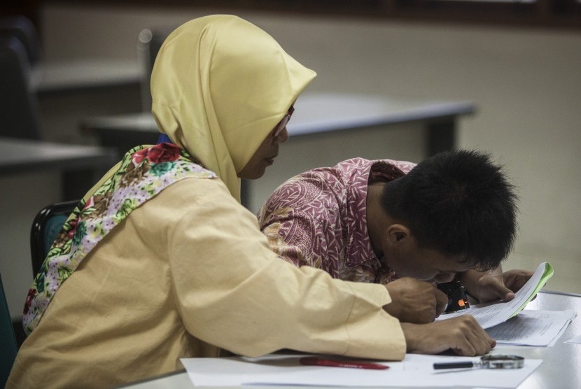 Petugas membantu peserta penyandang low vision saat ujian Seleksi Bersama Masuk Perguruan Tinggi Negeri (SBMPTN) 2017 di ruang F-MIPA Universitas Negeri Yogyakarta, (16/5).
