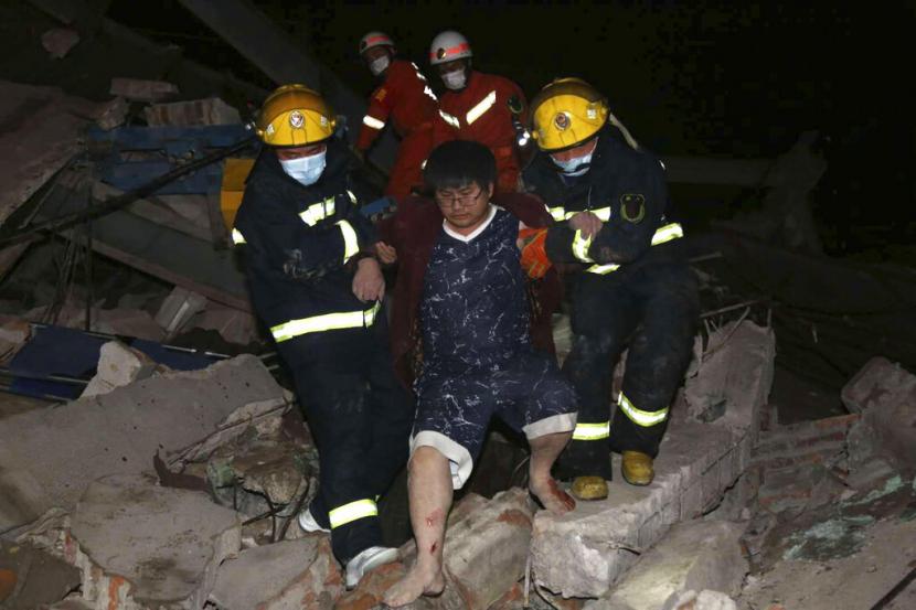 Petugas membantu salah satu korban selamat keluar dari reruntuhan hotel yang ambruk pada Sabtu (7/3) di Quanzhou, Provinsi Fujian. Hotel tersebut sedianya digunakan untuk observasi orang yang berkontak dengan pasien virus corona.