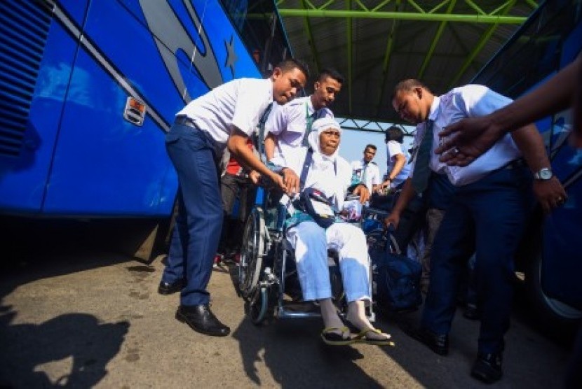 Petugas membantu seorang jamaah calon haji sebelum diberangkatkan ke Bandara Juanda menuju Mekah di Asrama Haji Sukolilo, Surabaya, Jawa Timur, Jumat (21/8). 