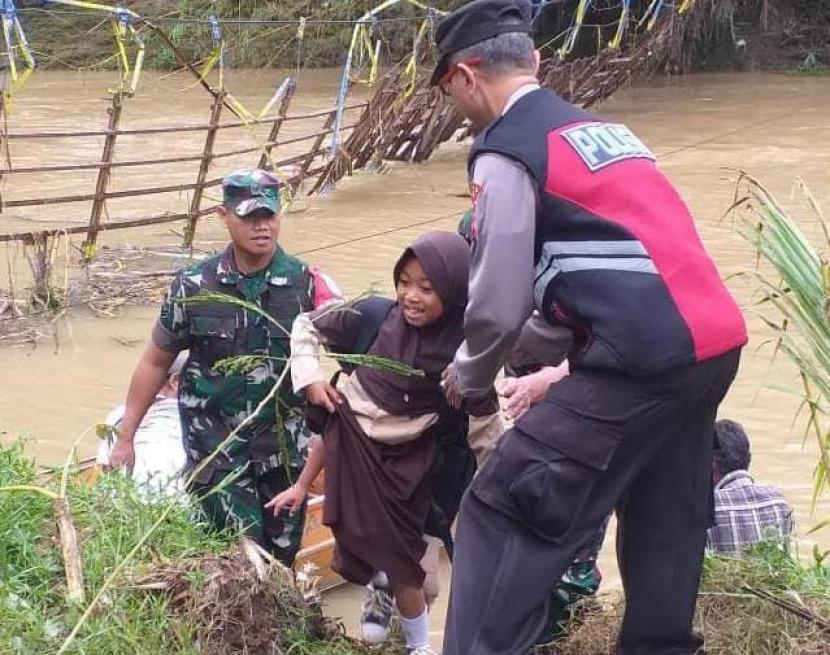 Petugas membantu siswa menyeberang Sungai Ciseel di Dusun Gunungsari, Desa Ciparay, Kecamatan Cidolog, Kabupaten Ciamis, Jumat (11/11/2022). 