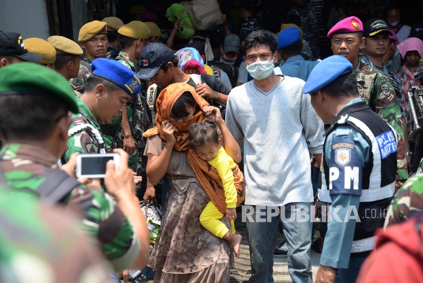   Petugas membantu warga eks anggota Gerakan Fajar Nusantara (Gafatar) yang baru turun dari KRI Banten saat tiba di Pelabuhan Kolinlamil Tanjung Priok, Jakarta Utara, Rabu (27/1) (Republika/Yasin Habibi).