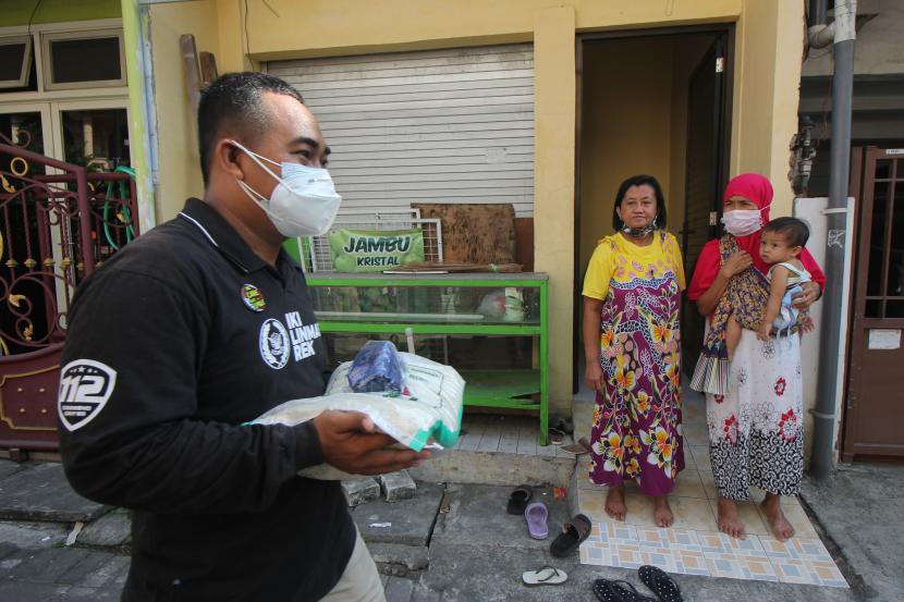 Petugas membawa bantuan beras untuk dibagikan kepada warga di Surabaya, Jawa Timur, Rabu (28/7/2021). Pembagian beras dari Kementerian Sosial kepada penerima bantuan tersebut untuk meringankan beban mereka yang terdampak oleh pandemi COVID-19.