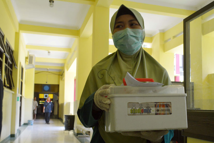 Petugas membawa boks berisi sampel urine milik pasien suspect ebola untuk dicek ke laboratorium di Rumah Sakit Umum Propinsi (RSUP) dr. Soedono Madiun, Jatim, Ahad (2/11). 