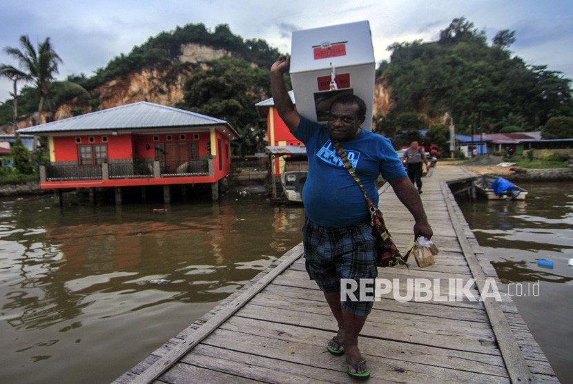 Petugas membawa kotak suara ketika melakukan pendistribusian logistik Pemilu 2019 di Kampung Kayu Pulo, Jayapura, Papua, Selasa (16/4/2019).