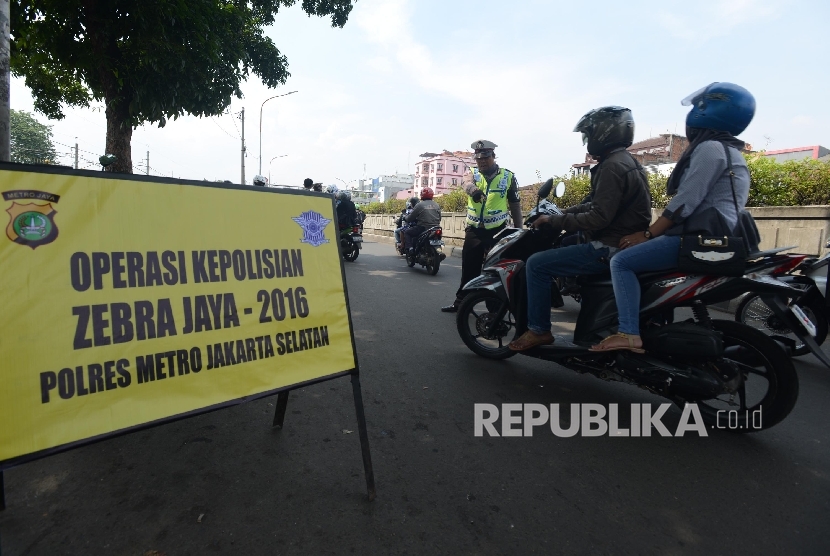 Petugas memberhentikan kendaraan untuk memeriksa kelengkapan surat kendaraan saat menggelar Operasi Zebra Jaya di Pasar Minggu, Kamis (17/11).