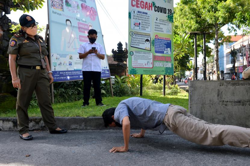 Petugas memberikan hukuman push up kepada warga yang terjaring sidak masker di Denpasar, Bali, Senin (24/1/2022). Petugas gabungan di wilayah Denpasar terus menggencarkan sidak masker untuk mendisiplinkan penerapan protokol kesehatan oleh masyarakat guna mencegah penyebaran pandemi COVID-19 khususnya varian Omicron.