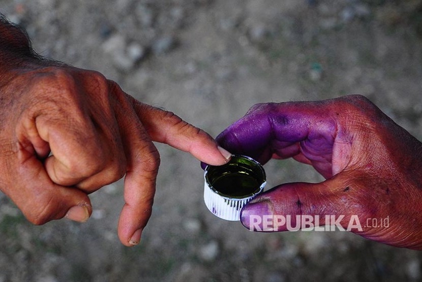 Petugas memberikan tinta pada jari salah satu warga saat pemilihan kepala desa (Pilkades) serentak di Kudus, Jawa Tengah.