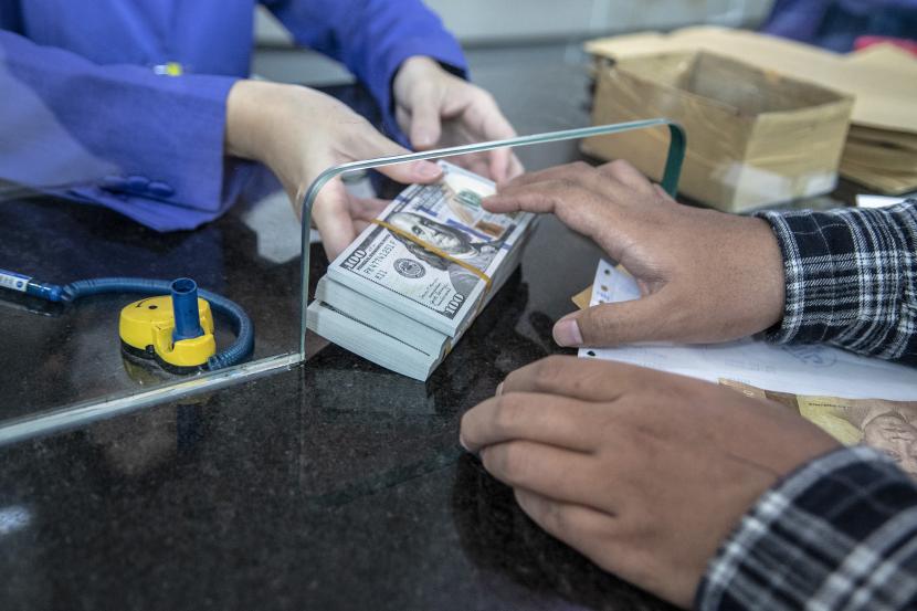 Petugas memberikan uang pecahan dolar AS kepada pembeli di gerai penukaran mata uang asing VIP (Valuta Inti Prima) Money Changer, Jakarta, Selasa (4/10/2022). Rupiah pada Selasa ditutup turun 31 poin atau 0,21 persen.