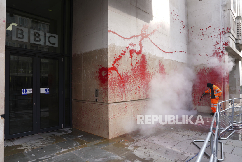 Petugas membersihkan bekas cat semprot berwarna merah darah di kantor BBC di London, Senin (17/2/2025).