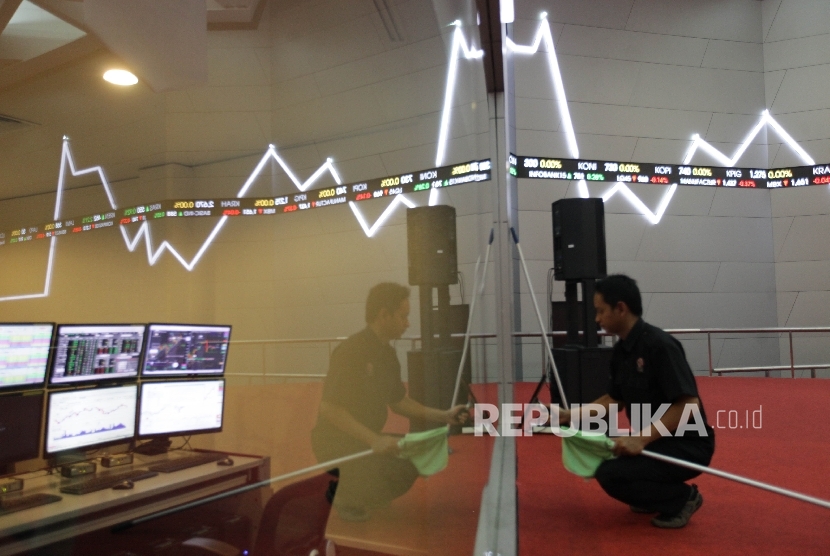 Petugas berdiri di dekat papan elektronik yang menunjukkan pergerakan indeks harga saham gabungan (IHSG) di gedung Bursa Efek Indonesia.