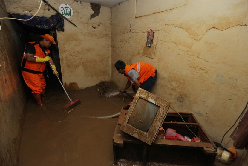 Petugas membersihkan endapan lumpur sisa banjir di perumahan Pengadegan, Jakarta, Kamis (2/1/2020). Banjir yang melanda permukiman warga di kawasan tersebut berangsur surut, dan warga mulai membersihkan rumah dari endapan lumpur sejak banjir menggenangi rumah. 