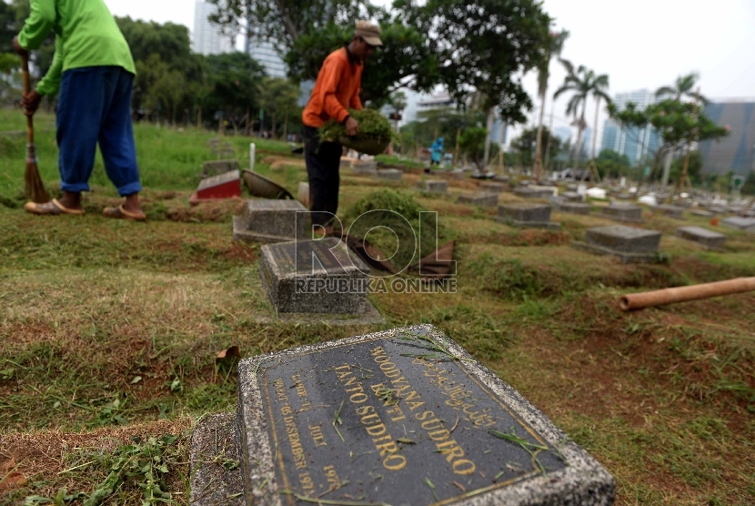 Petugas membersihkan komplek makam di TPU Menteng Pulo, Jakarta Selatan, Jumat (27/11).