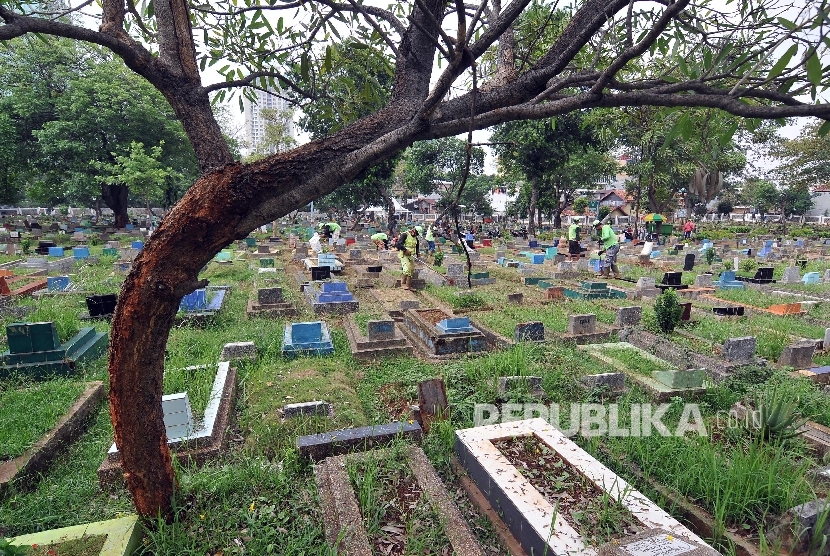 Petugas membersihkan makam di Tempat Pemakaman Umum (TPU) Karet Bivak, Tanah Abang, Jakarta Pusat, Jumat (6/10).