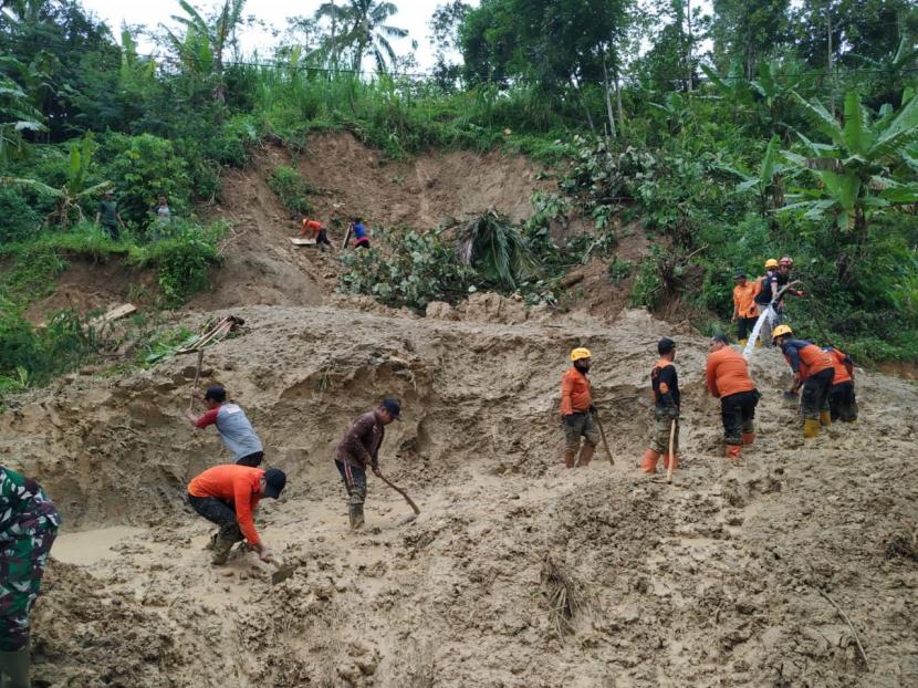Petugas membersihkan material longsor yang menutup akses jalan alternatif penghubung Tasikmalaya-Pangandaran, tepatnya di Dusun Cimandar, Desa Cisarua, Kecamatan Cineam, Kabupaten Tasikmalaya, Kamis (21/1) siang. 