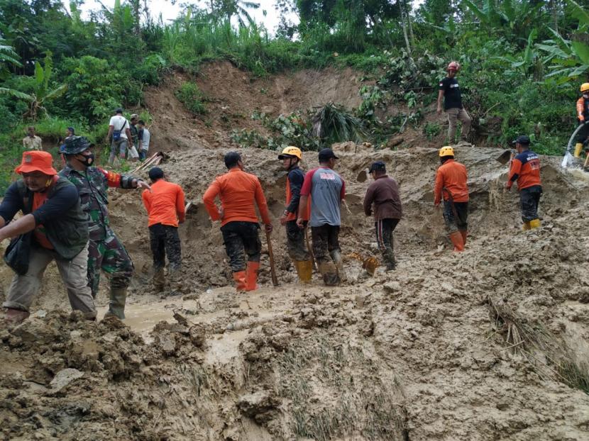 Petugas membersihkan material longsor yang menutup akses jalan alternatif penghubung Tasikmalaya-Pangandaran, tepatnya di Dusun Cimandar, Desa Cisarua, Kecamatan Cineam, Kabupaten Tasikmalaya, Kamis (21/1) siang.