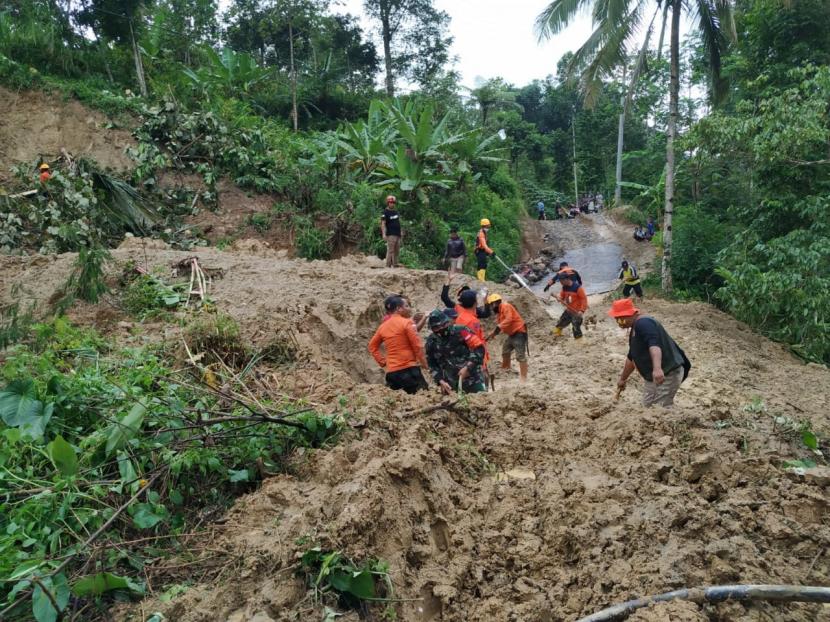 Petugas membersihkan material longsor yang menutup akses jalan alternatif penghubung Tasikmalaya-Pangandaran, tepatnya di Dusun Cimandar, Desa Cisarua, Kecamatan Cineam, Kabupaten Tasikmalaya, Kamis (21/1) siang.