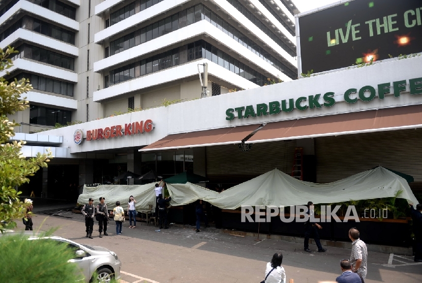 Petugas membersihkan pecahan kaca bekas ledakan di Starbucks Coffe, Jakarta, Jumat (15/1).