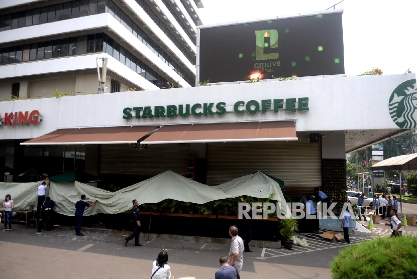 Petugas membersihkan pecahan kaca bekas ledakan di Starbucks Coffe, Jakarta, Jumat (15/1). 