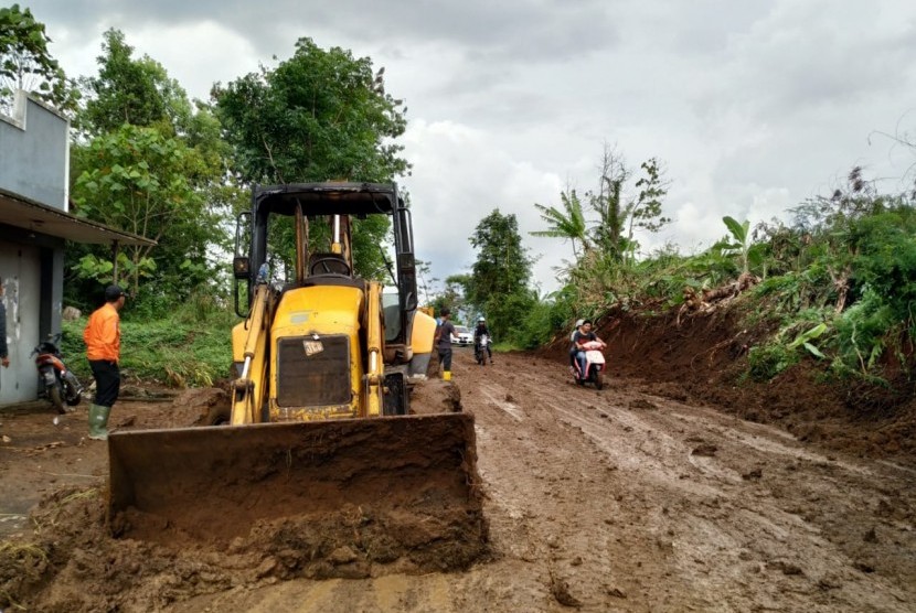 Petugas membersihkan sisa material longsoran yang menutup badan Jalan Cisinga, tepatnya di Kampung Sukasukur, Desa Karangsembung, Kecamatan Jamanis, Kabupaten Tasikmalaya, Rabu (18/12). 