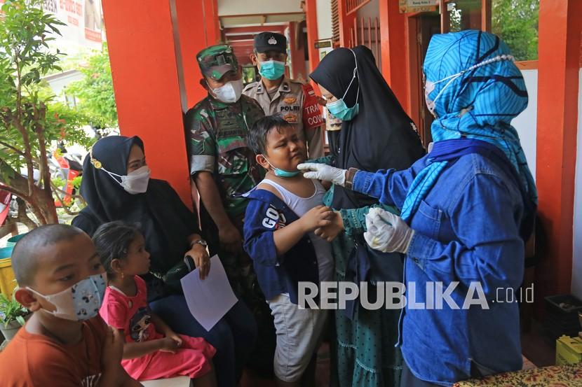 Petugas memenangkan seorang anak sebelum mengikuti vaksinasi COVID-19 di SDN 6 Margadadi, Indramayu, Jawa Barat, Kamis (6/1/2022). Vaksinasi COVID-19 bagi anak umur 6-11 tahun tersebut bertujuan mempercepat dan memperluas pelaksanaan PTM (Pembelajaran Tatap Muka) di seluruh wilayah Indonesia. 