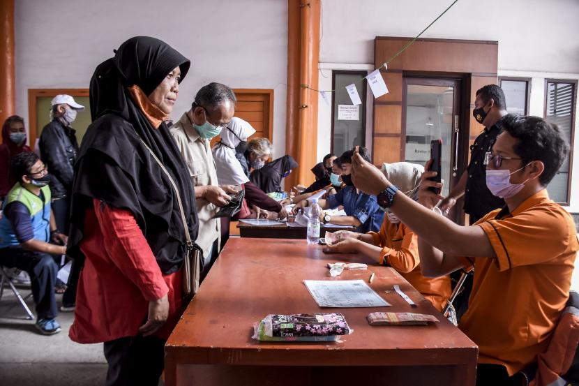 Petugas memeriksa data diri warga saat penyaluran bantuan sosial (bansos) Provinsi Jawa Barat Tahap ke-IV di Kantor Pos Bandung, Jalan Asia Afrika, Kota Bandung.