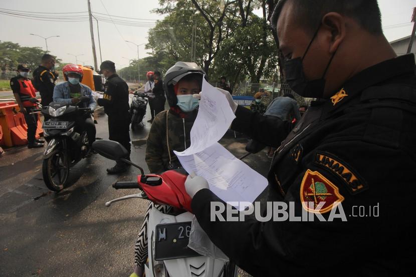 Petugas memeriksa dokumen surat izin keluar masuk (SIKM) milik warga yang akan masuk ke Surabaya di akses keluar Jembatan Suramadu, Surabaya, Jawa Timur, Senin (21/6/2021). Warga dari Madura ke Surabaya dan sebaliknya wajib menunjukkan surat izin keluar masuk (SIKM) yang dilampiri hasil tes cepat antigen non reaktif kepada petugas penyekatan saat melintas di Jembatan Suramadu dan menyeberang dari Pelabuhan Kamal.