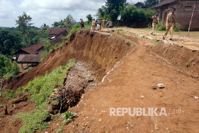 Petugas memeriksa jalan desa yang ambrol terseret longsor di Desa Sidomulyo, Tulungagung, Jawa Timur, Senin (8/4/2019).