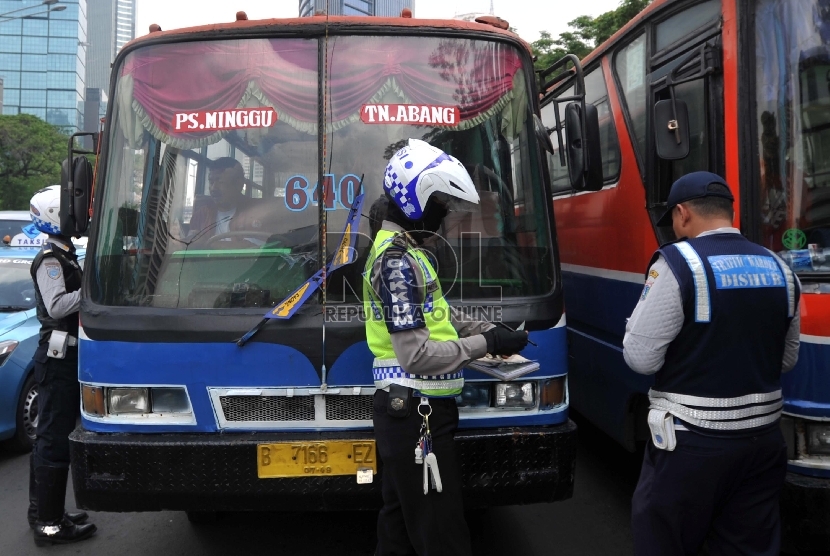 Petugas memeriksa kelengkapan surat kendaraan sopir Metro Mini saat razia gabungan angkutan umum di Jalan Sudirman, Jakarta, Senin (7/12). (Republika/Yasin Habibi)