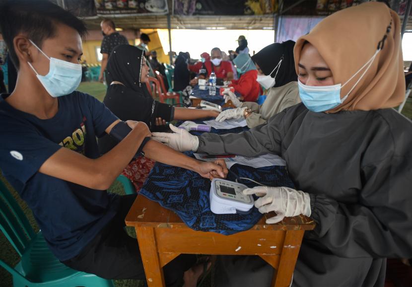 Petugas memeriksa kesehatan warga saat vaksinasi COVID-19 untuk pedagang dan sopir angkot di Pasar Induk Rau, Serang, Banten, Kamis (18/11/2021). Pemda setempat menggencarkan vaksinasi di pasar-pasar untuk memberi kemudahan akses bagi para pedagang dan sopir angkot serta warga di sekitar lokasi yang belum mendapat vaksin COVID-19 guna mempercepat penuntasan pencapaian kekebalan komunal (Herd Immunity) dan Indonesia bebas COVID-19.