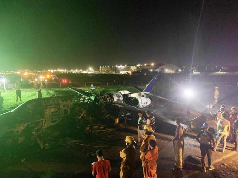 Petugas memeriksa pesawat carter Lionair yang jatuh di Bandara Internasional Ninoy Aquino (NAIA) pada Ahad (29/3). Seluruh penumpang pesawat dikabarkan tak selamat.