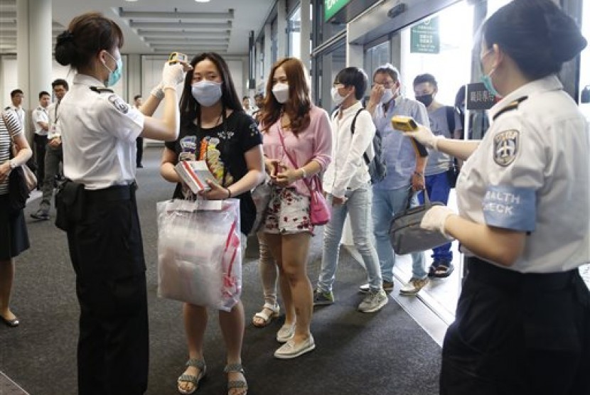 Petugas memeriksa suhu badan para penumpang yang baru tiba dari Busan Korea Selatan, saat mendarat di Bandara Hong Kong, Jumat (5/6), untuk mengantisipasi merebaknya kasus MERS.