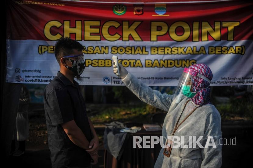 Petugas memeriksa suhu tubuh di titik pemeriksaan pelaksanaan Pembatasan Sosial Berskala Besar (PSBB) di Perbatasan Kota Bandung, Jawa Barat, Kamis (23/4/2020). Titik pemeriksaan di perbatasan Kota Bandung tersebut memeriksa kendaraan dari arah Garut, Tasik, dan Sumedang yang akan masuk ke Kota Bandung selama pelaksanaan PSBB di Bandung Raya dua minggu ke depan. 