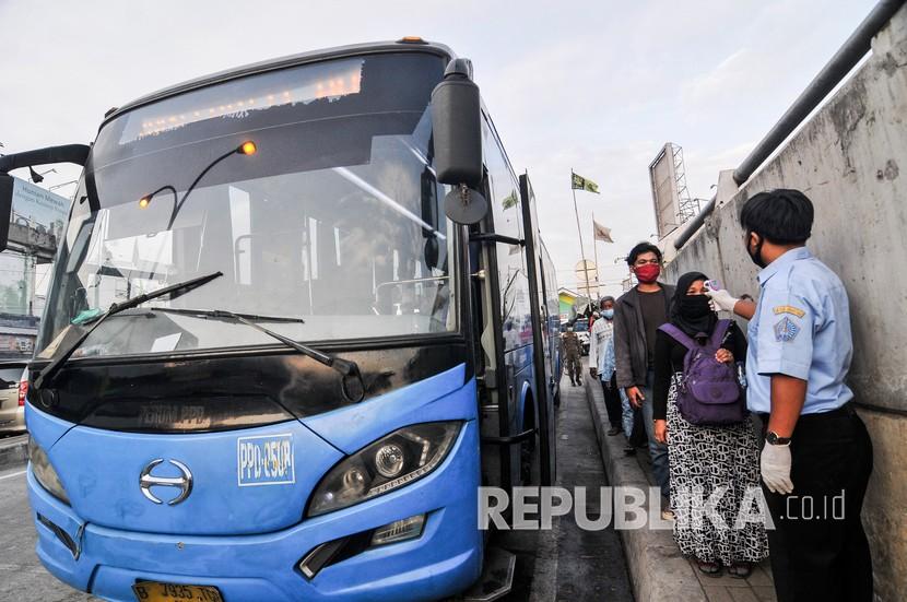 Petugas memeriksa suhu tubuh penumpang sebelum menaiki bus bantuan pemprov DKI Jakarta di Stasiun Tambun, Kabupaten Bekasi, Jawa Barat, Senin (22/6/2020). 