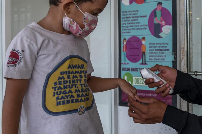 Petugas memeriksa suhu tubuh seorang anak sebelum memasuki kawasan perbelanjaan di Palu, Sulawesi Tengah, Kamis (24/6/2021). Sejumlah lembaga penelitian bidang kesehatan memperingatkan kerentanan anak terinfeksi COVID-19 yang saat ini berasio 1 : 9 kasus akan meningkat setelah ditemukannya varian baru B16.17 atau Varian Delta.