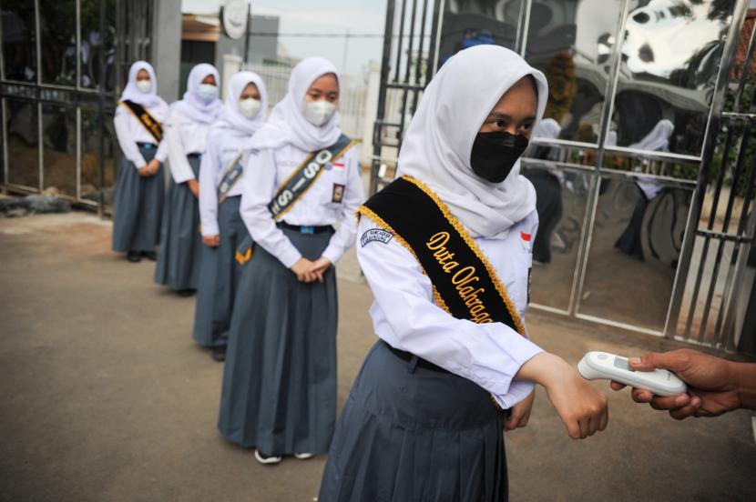 Petugas memeriksa suhu tubuh siswa sebelum mengikuti pembelajaran tatap muka terbatas di SMAN 1 Rancaekek, Kabupaten Bandung, Jawa Barat, Senin (6/9/2021). 