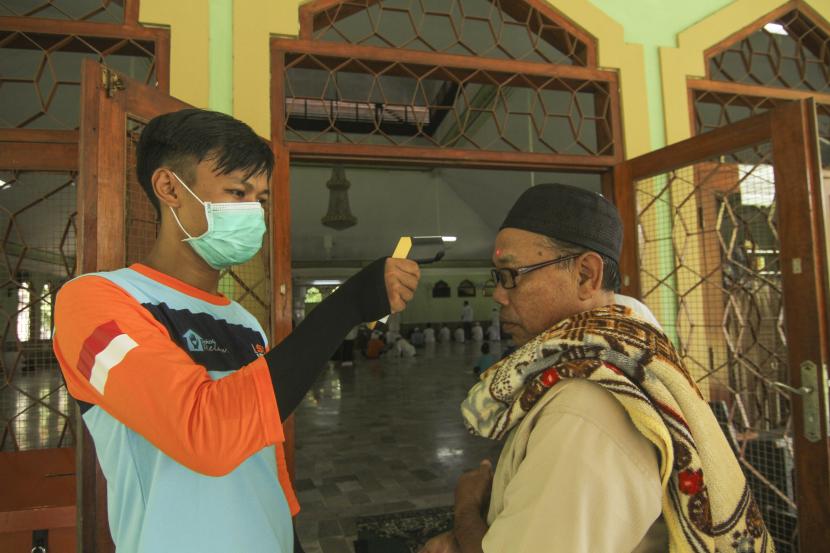 Petugas memeriksa suhu tubuh warga sebelum mengikuti shalat berjamaah di Masjid Nurussalam, Depok, Jawa Barat, Jumat (20/03/2020).