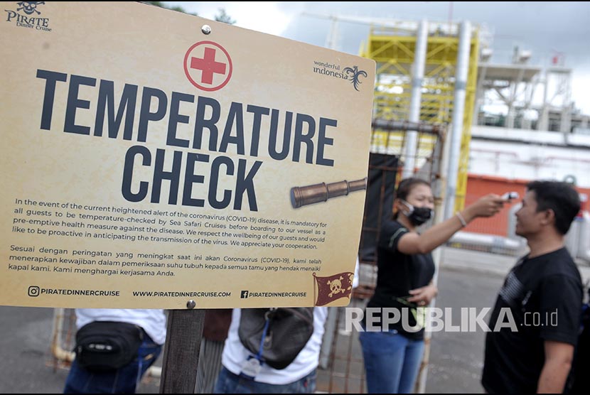 Petugas memeriksa suhu tubuh wisatawan