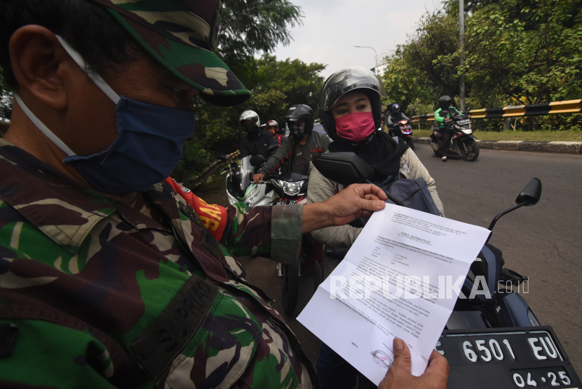 Petugas memeriksa Surat Izin Keluar Masuk (SIKM) Jakarta terhadap pengendara kendaraan bermotor yang melintas menuju Jakarta di perbatasan wilayah, Depok, Jawa Barat.
