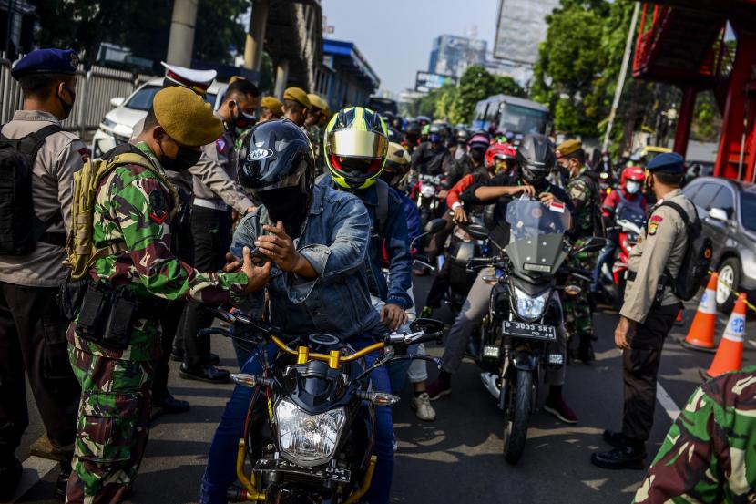 Petugas memeriksa surat tanda registrasi pekerja (STRP) atau surat tugas pengendara saat diberlakukan penyekatan di Jalan Raya Mampang Prapatan, Jakarta.
