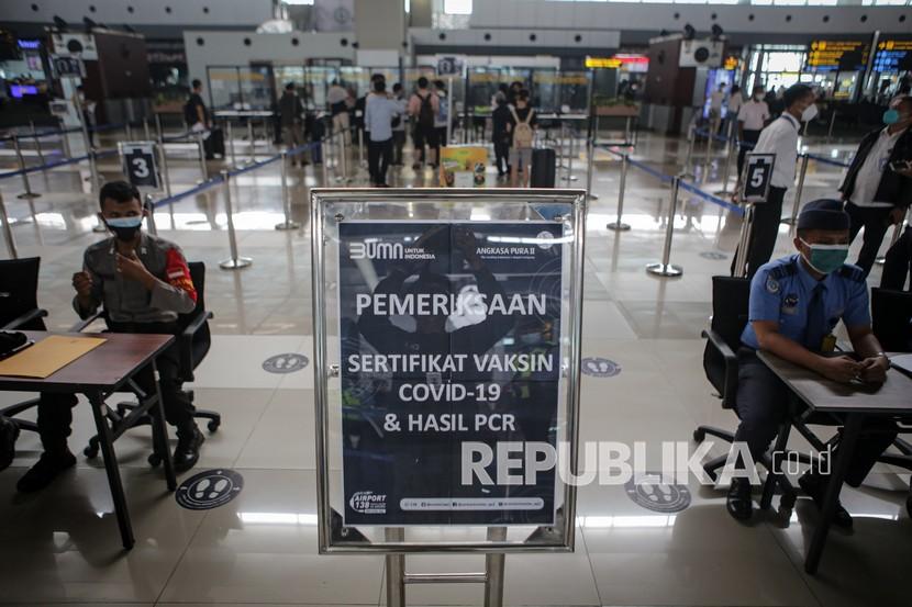 Petugas memeriksa surat vaksinasi dan hasil tes PCR calon penumpang pesawat