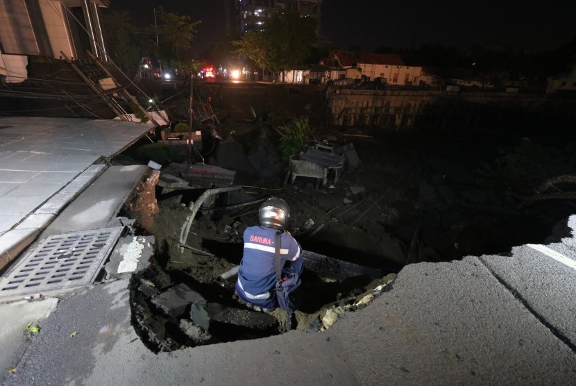 Petugas memeriksa tanah amblas di Kawasan Gubeng Surabaya, Jawa Timur, Selasa (18/12/2018). Petugas masih mencari kemungkinan adanya korban di lokasi jalan amblas yang diduga karena pembangunan gedung dikawasan tersebut.