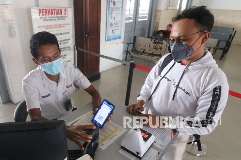 Petugas memindai kode batang (QR Code) menggunakan aplikasi boarding yang terintegrasi dengan aplikasi PeduliLindungi milik calon penumpang kereta api lokal di Stasiun Kota Kediri, Jawa Timur.