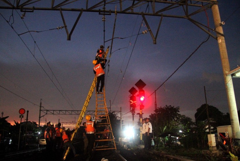 Petugas memperbaiki kabel listrik aliran atas yang mengalami korsleting di lintasan kereta api Tambun-Bekasi, Jawa Barat, Selasa (2/4).